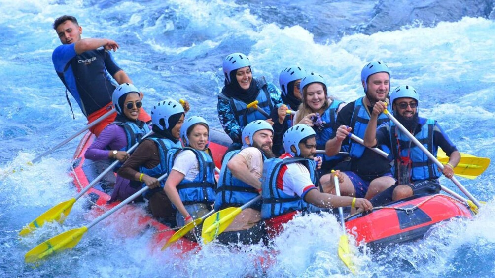 A group of people in a red raft navigating through white water rapids. 4
