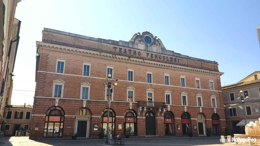 Teatro Pergolesi, a historic building with a classical facade, arched windows, and a prominent clock. 3