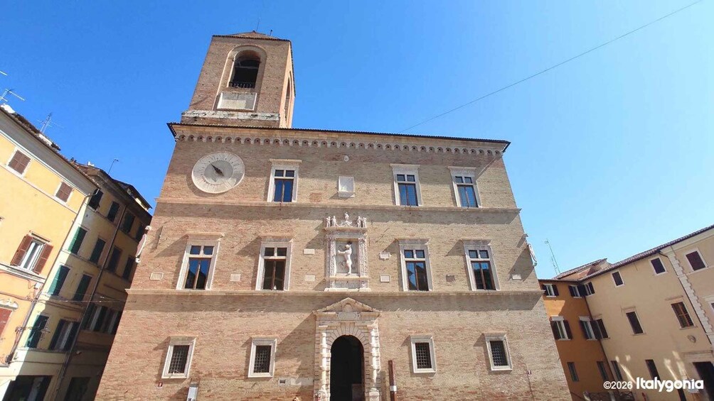 A historic building with a clock tower, arched windows, and a central entrance. 2