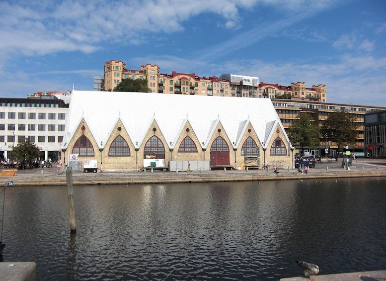 A waterfront building with a white roof and arched windows, a river in the foreground, and a cityscape in the background. 4