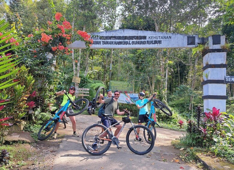 A group of people with bicycles at a trail entrance with a sign indicating a national park. 3