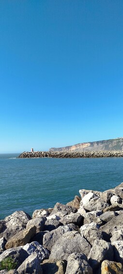 A rocky coastline with a lighthouse and cliffs in the background. 1