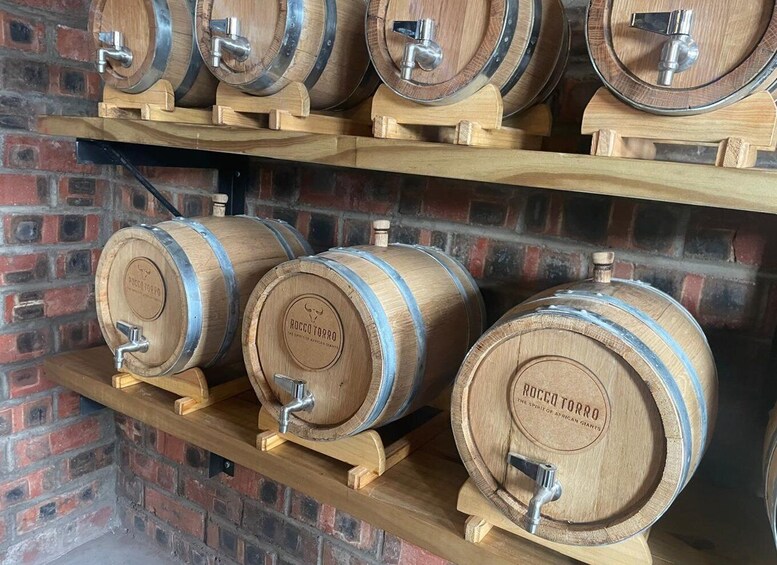 Wooden barrels with taps on shelves against a brick wall. 3