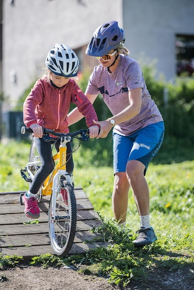 A person assisting another on a bicycle. 1