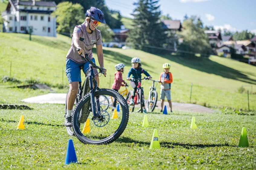 A person riding a mountain bike on a grassy trail with cones, surrounded by houses and trees. 4