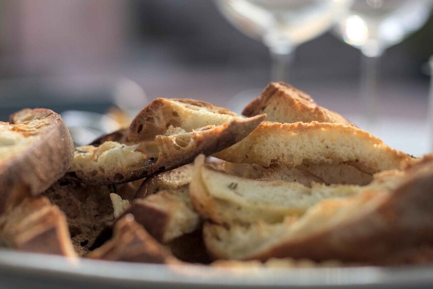 A plate of toasted bread with a glass of white wine in the background. 3
