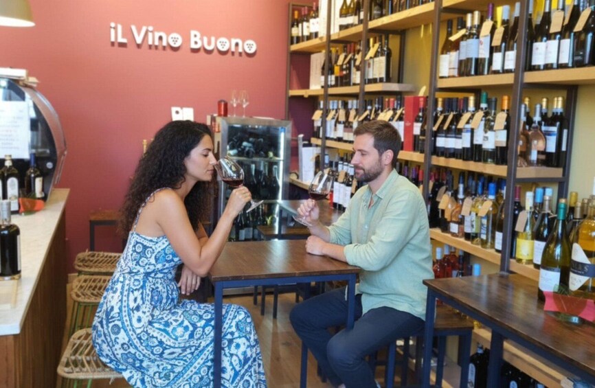 Two people in a wine shop with shelves of wine bottles. 3