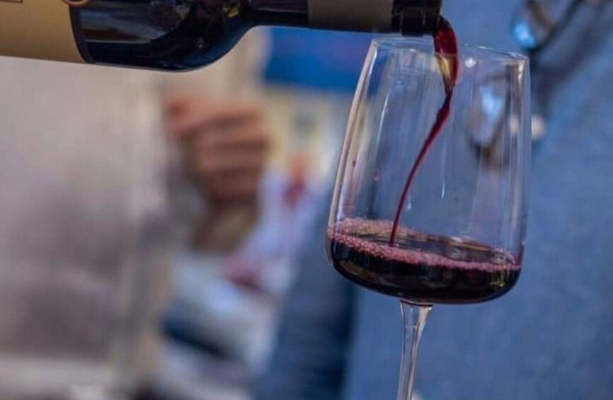 A wine glass being filled with red wine. 2