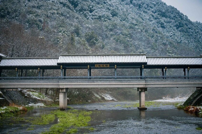A traditional Japanese bridge over a river with snow-covered trees in the background. 3