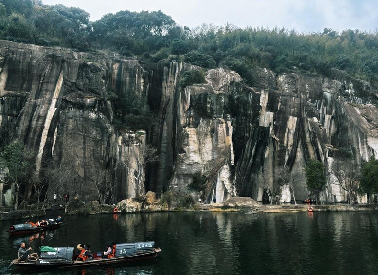 A rocky cliff with a boat on a calm river in front. 4