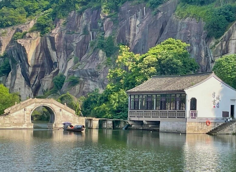 A traditional building by a river with a stone bridge in the foreground. 5