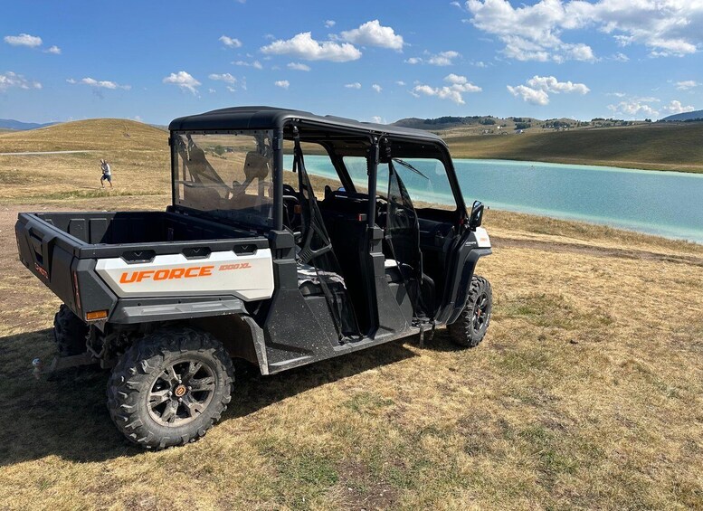 A UFORCE 3XL off-road vehicle parked on a grassy field near a body of water. 5