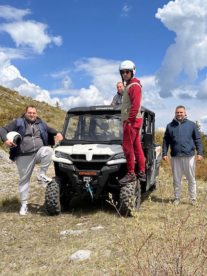 Four people standing around a white off-road vehicle with the brand name 'CEMOTO' on the front. 2