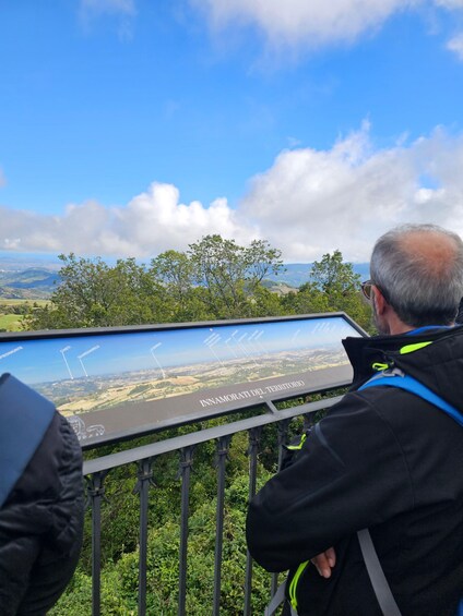A man looking at a digital map with a scenic view of a valley and mountains in the background. 4