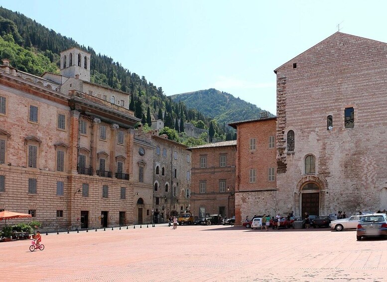 A historic square with buildings, a paved area, and a mountain in the background. 3