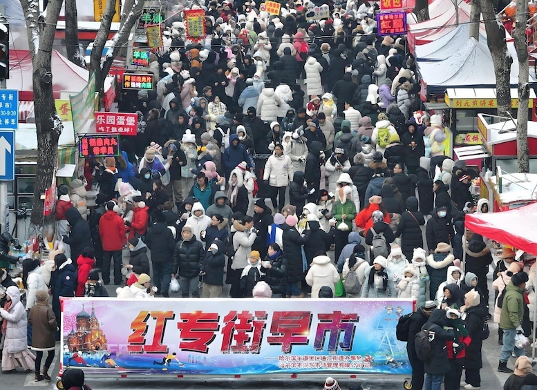A crowded street with people gathered around a large banner. 2
