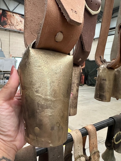 A hand holding a metallic object with a textured surface, possibly a part of a larger mechanism or equipment. 2