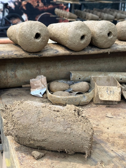 A collection of cylindrical objects, possibly made of clay, arranged on a wooden surface. 4