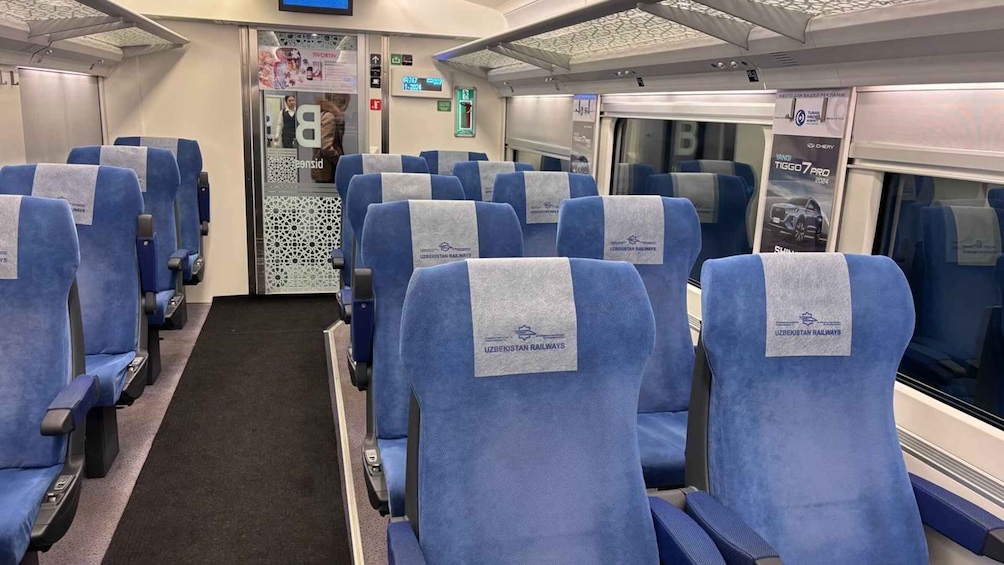 A train carriage with blue seats, a door, and a window displaying a car advertisement. 2