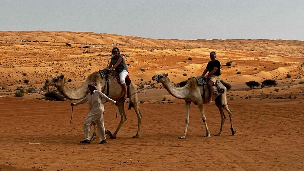 Three camels with riders in a desert landscape. 5