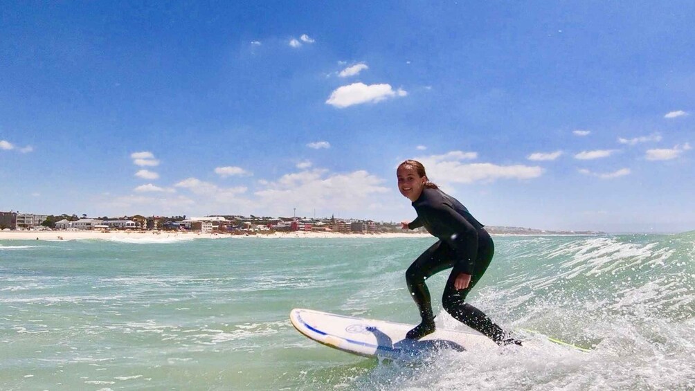 A person surfing on a wave with a coastal town in the background. 1