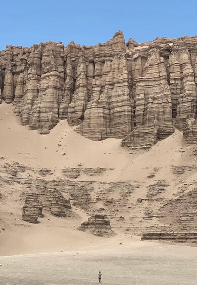 A person walking on a desert with layered rock formations. 4