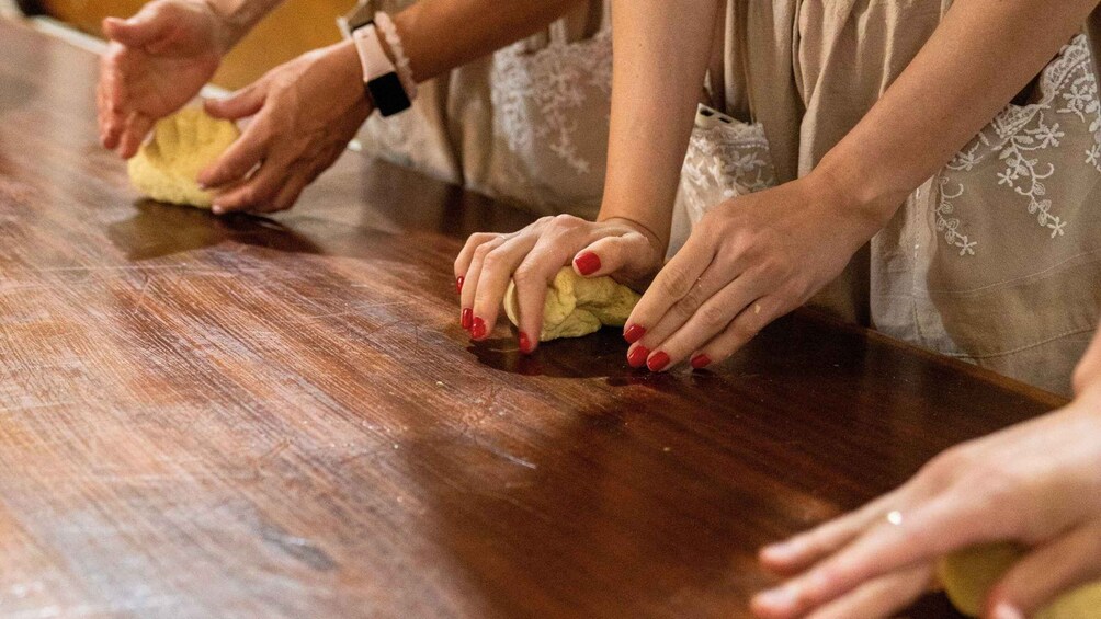 Hands kneading dough on a wooden surface. 4