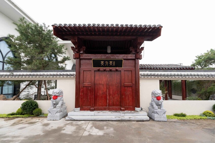 A traditional Chinese gate with a red door and a black plaque, flanked by two stone lion statues. 3