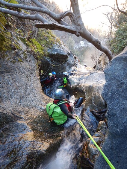 A group of people rappelling down a rocky cliff. 1