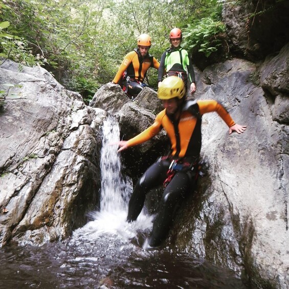 Three people rappelling down a rocky waterfall. 3