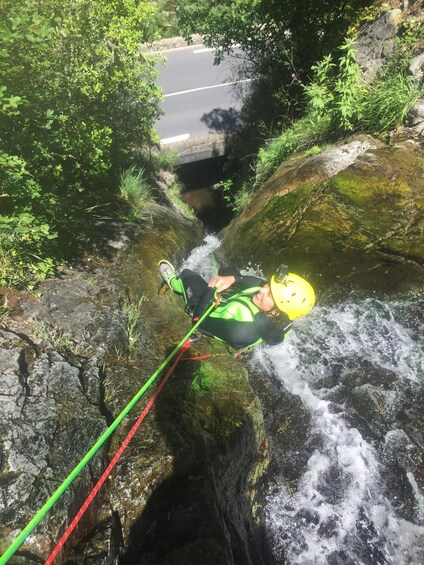 A person rappelling down a rocky cliff with a river below. 2