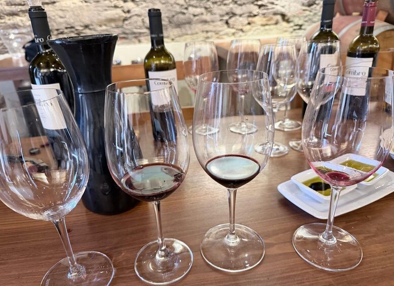 A table with wine glasses and bottles, some filled with wine, and a stone wall in the background. 5