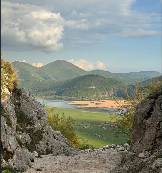 A mountainous landscape with a river, green fields, and rocky terrain. 5