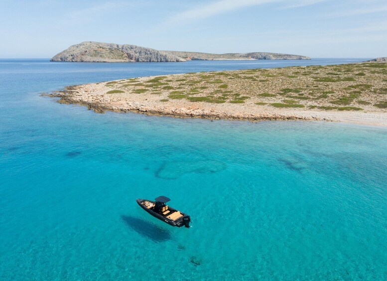 A boat on clear turquoise water, a rocky shoreline, and distant islands. 5