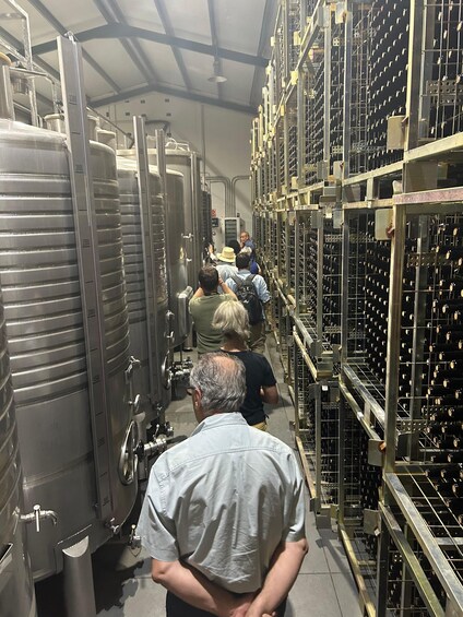 A warehouse with large stainless steel tanks and racks of bottles. 3