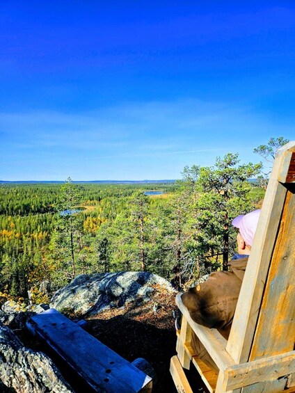 A wooden chair overlooking a forested landscape with a lake in the distance. 4