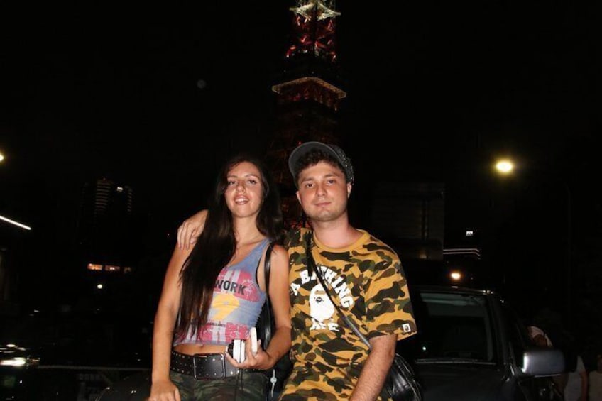 Two people standing in front of a decorated structure at night. 3