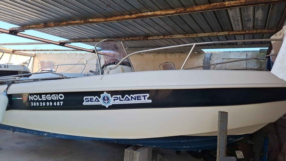 A boat with the name 'NOLEGGIO' and 'SEA PLANET' written on its side, docked in a covered area with other boats. 3