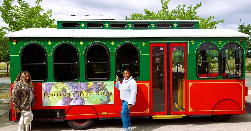 A colorful trolley with a vineyard advertisement, parked outdoors. 2