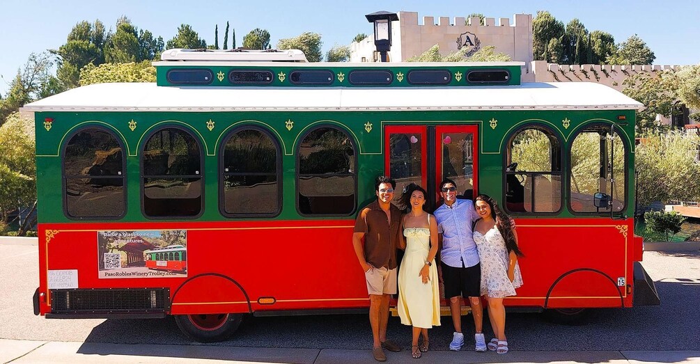 A red and green trolley with a group of people standing in front of it. 4