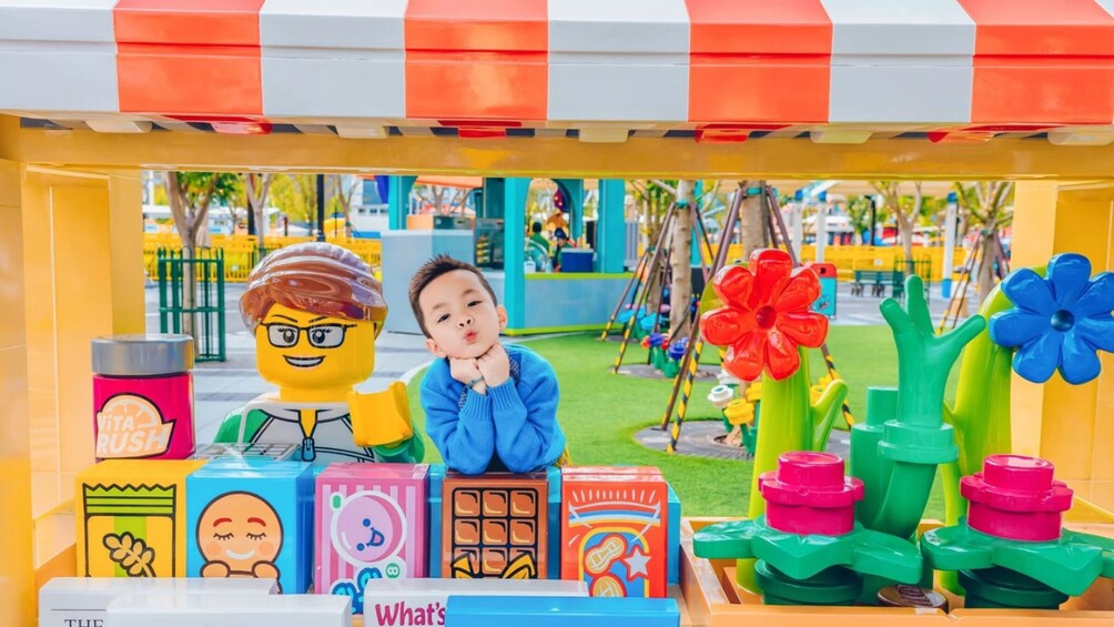 A colorful play area with a vending machine, a child, and a large flower decoration. 3