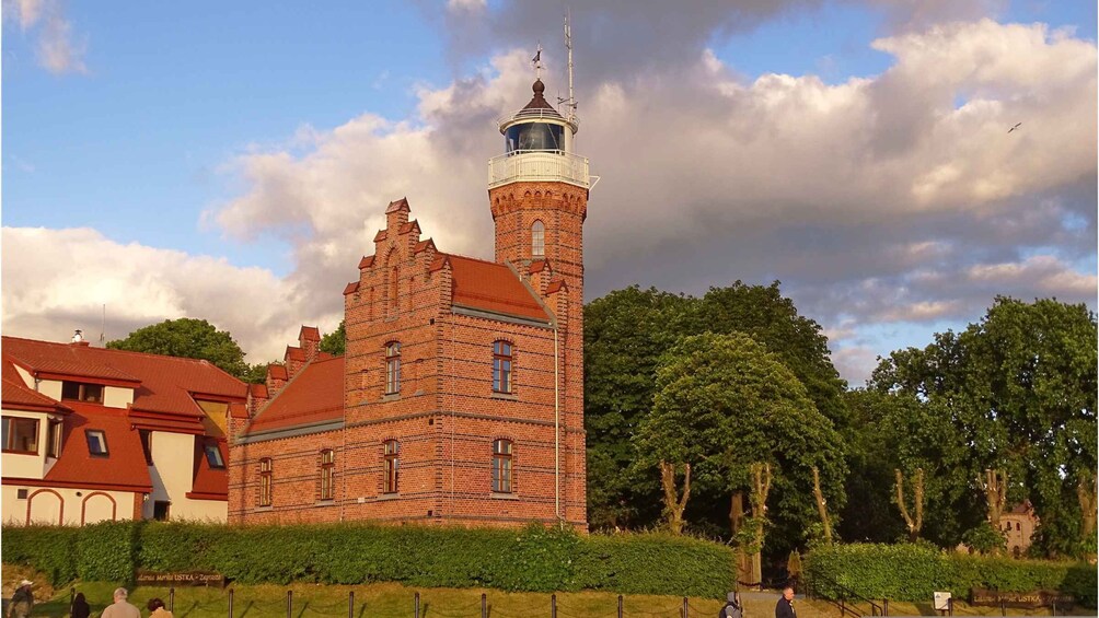 A historic brick building with a tower, surrounded by trees and a fenced area. 5