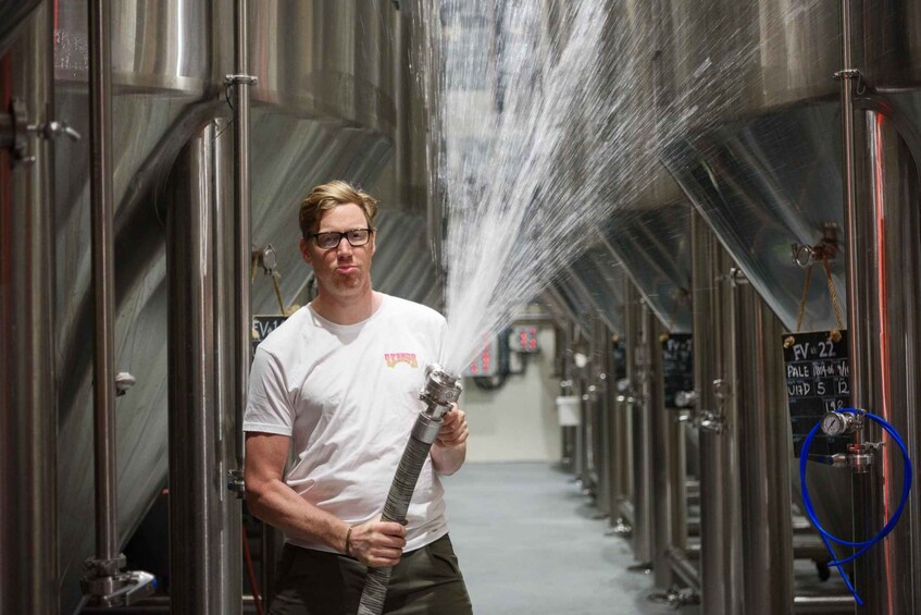 A person holding a hose spraying water in a brewery. 3