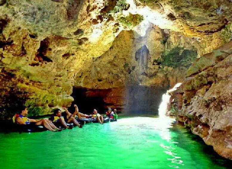 A group of people sitting on tubes in a cave with a waterfall. 2