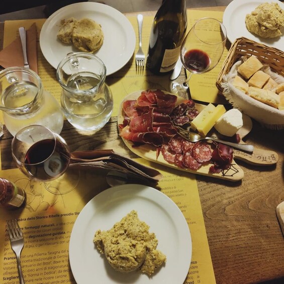 A table with plates of food, a bottle of wine, glasses, and a menu. 2