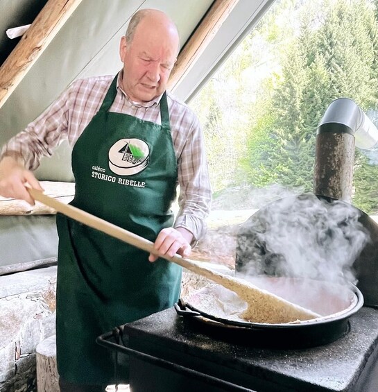 A person in a green apron cooking with a large pot on a stove, steam rising from the pot. 4