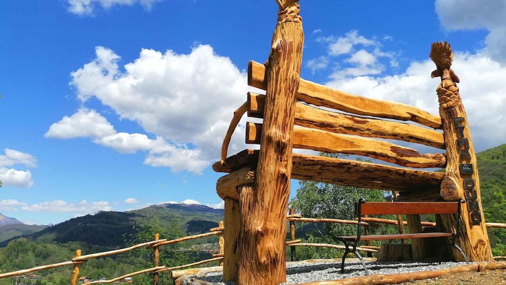 A rustic wooden bench with a view of a mountainous landscape. 1