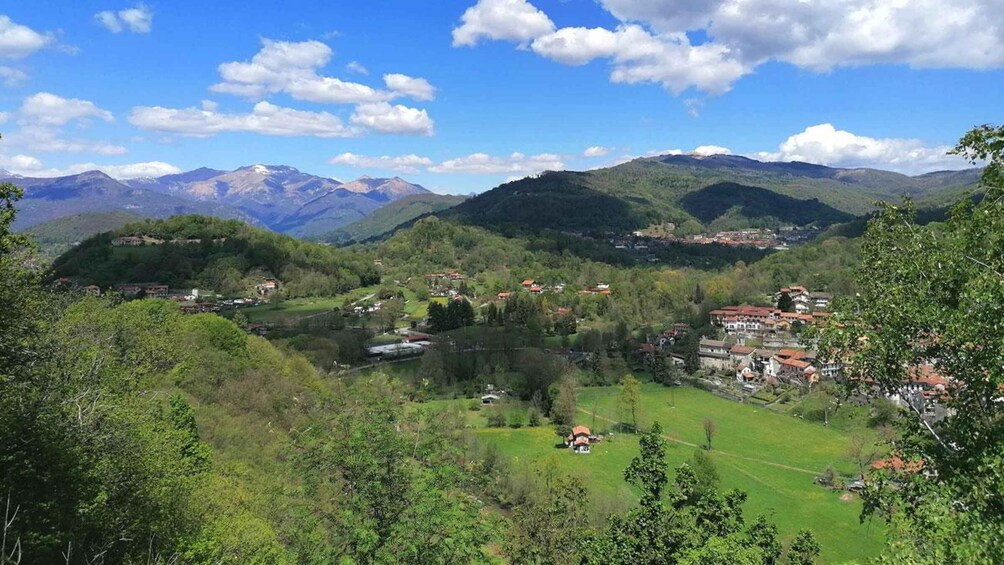 A mountainous landscape with a village nestled among the hills, a lake, and a clear blue sky. 4
