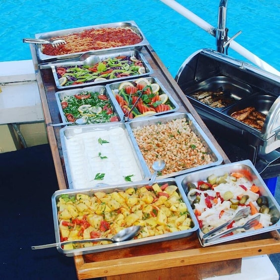 A buffet table with various food options including pasta, salads, rice, and grilled items. 2
