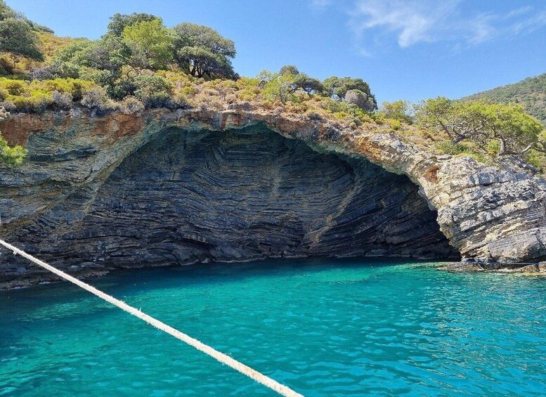 A rocky coastline with a clear blue sea, a rope bridge, and lush greenery. 4